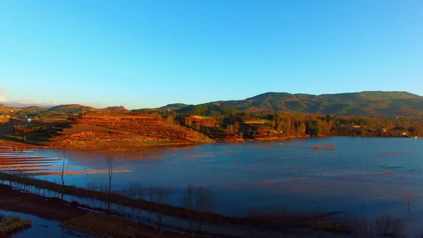 Scenic view of a lake surrounded by hills and trees under a clear blue sky