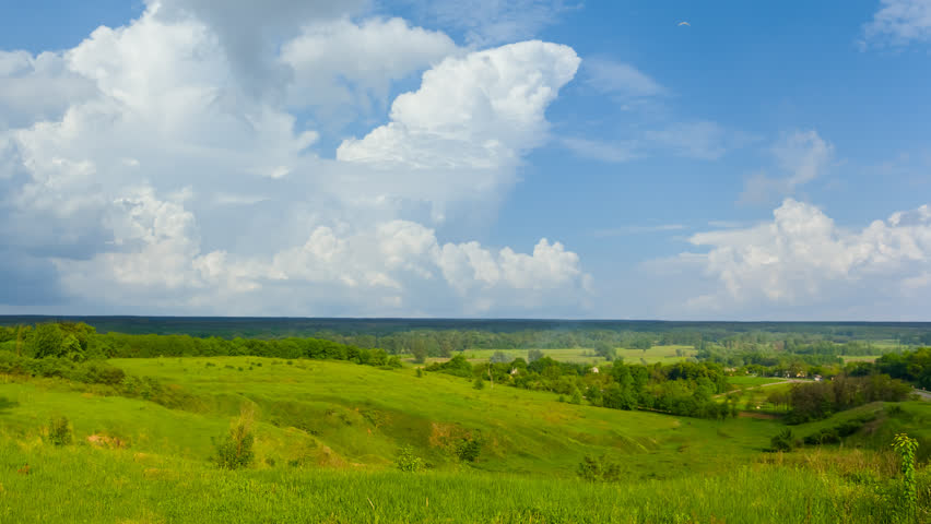 wide green hills under a dense cloudy sky, summer rural time lapse scene