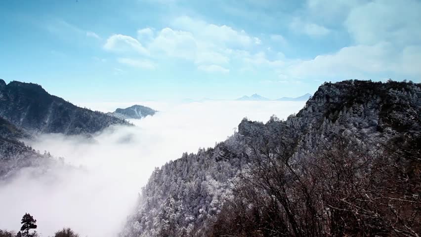 Scenic winter landscape with snow covered mountains, trees and fog