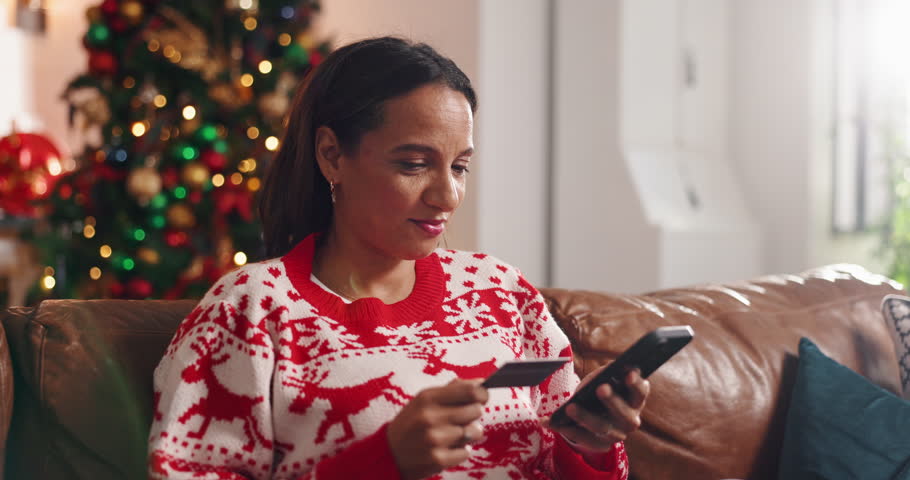 Credit card, Christmas and woman on sofa with phone for online shopping, festive season and deals. Debit, cellphone and female person with internet store, xmas discount and gift in home living room