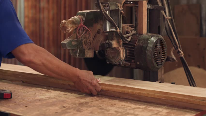 Carpenter Uses Industrial Circular Saw To Cut Wood Plank As African American Male Woodworker Works In Sawmill Workshop Focused On Timber Manufacturing And Professional Furniture Craft With Precision