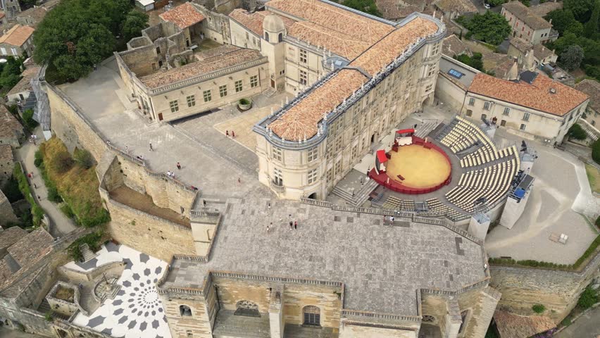 Aerial drone view of Grignan Castle surrounded by lush greenery and historic village in Provence, France – medieval fortress with scenic landscape and vibrant natural surroundings