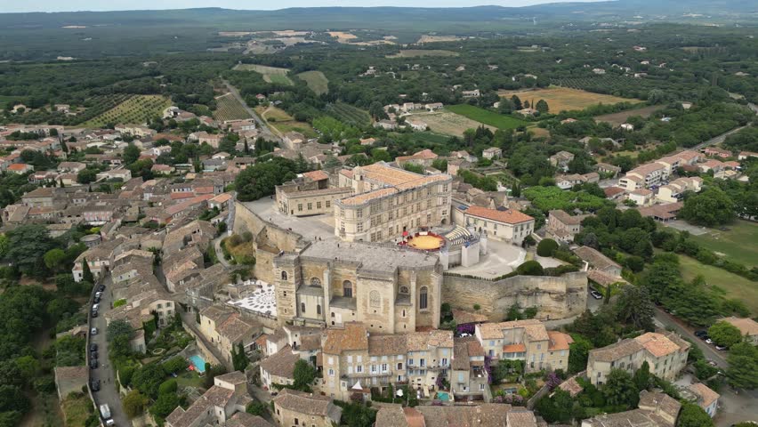 Aerial drone view of Grignan Castle surrounded by lush greenery and historic village in Provence, France – medieval fortress with scenic landscape and vibrant natural surroundings
