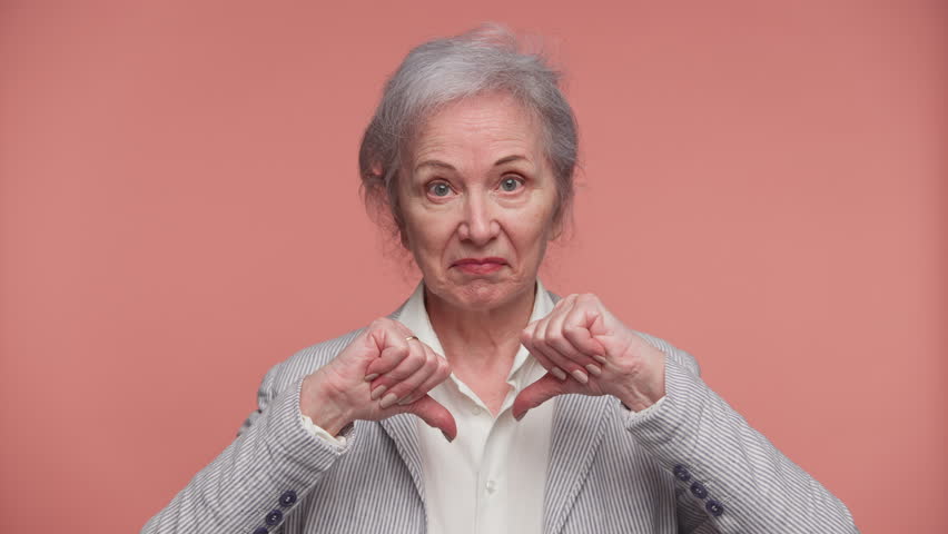 Serious senior woman giving thumbs down