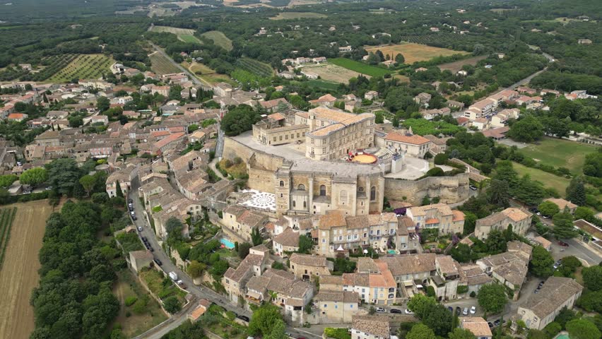 Aerial drone view of Grignan Castle surrounded by lush greenery and historic village in Provence, France – medieval fortress with scenic landscape and vibrant natural surroundings