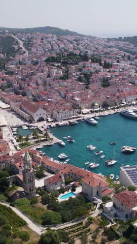 Picturesque cityscape of Hvar old town with harbor and waterfront promenade, Hvar island, Croatia. Aerial, Vertical Video