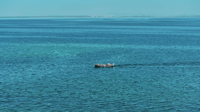 Man fishing on a boat in the sea in Izmir - drone shot of the fisherman 4k