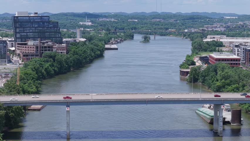 Static aerial view of a river, bridges, cityscape, and lush green surroundings over Cumberland River in Nashville, TNNashville