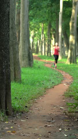 4K Sports lifestyle. Road runner young asian woman running on a path in the park. Jogging on a sunny day of summer in Taiwan. Exercising Concept. Sports lifestyle. Slider Camera Movement