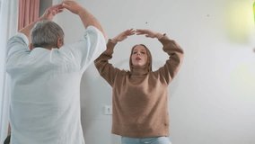 Adult daughter teaching her elderly father doing yoga tree pose with raised arms. Wellness at home, family support, senior fitness, intergenerational bonding, healthy lifestyle, active seniors - Powered by Shutterstock - Get 15% off with code: PIKWIZARD15