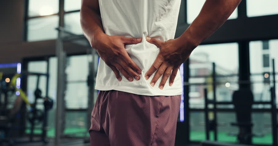 Hands, fitness and hip of man in gym with pain, discomfort and injury for workout, training and exercise. Sports, health risk and person with joint ache, muscle strain and inflammation for accident