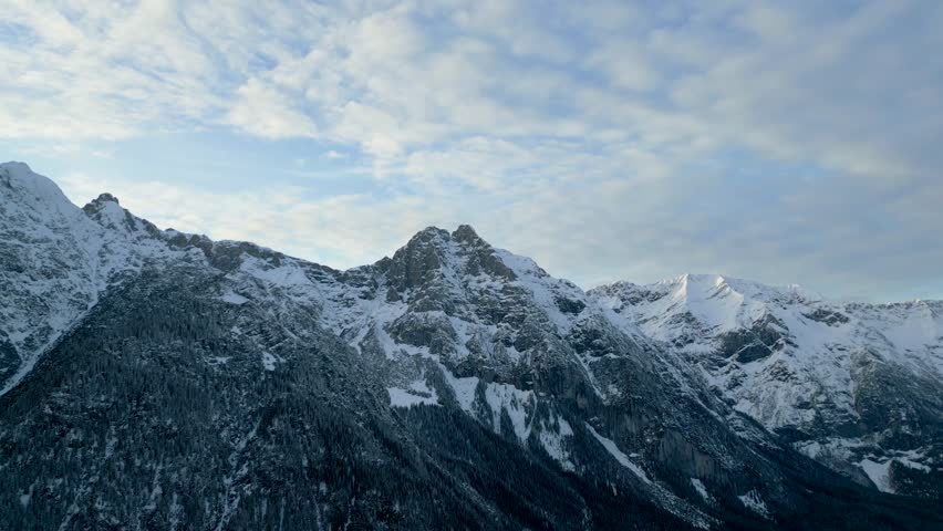 A Majestic, Static View of a Snow-Covered Mountain Range under a Partly Cloudy Sky, a Beautiful and Serene Winter Landscape Scene