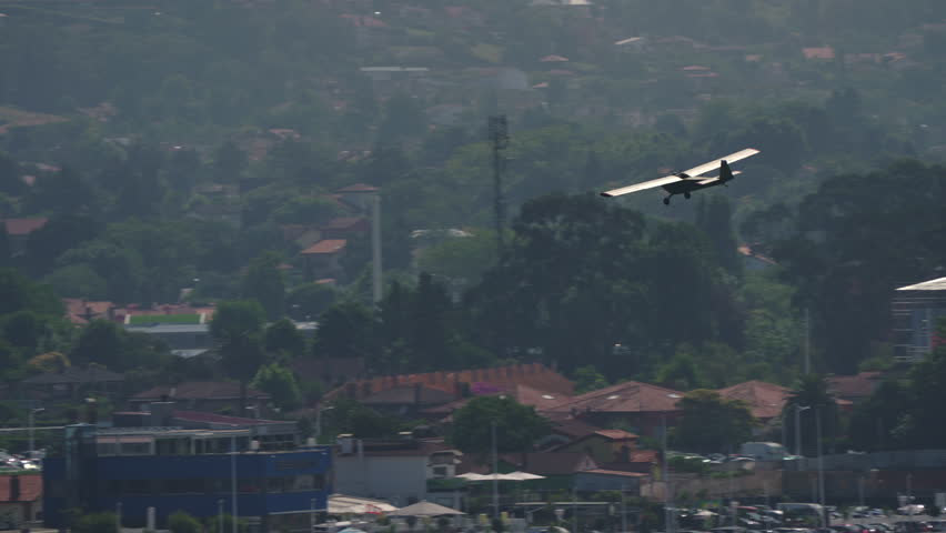 Old vintage training airplane with wooden body flying over city buildings with open cockpit and no glass cover