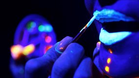 Close up of female hand painting girl's lips with glowing paint under neon light. Fluorescent makeup. - Powered by Shutterstock - Get 15% off with code: PIKWIZARD15