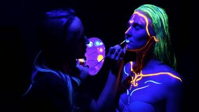Close up of female hand painting girl's lips with glowing paint under neon light. Fluorescent makeup. - Powered by Shutterstock - Get 15% off with code: PIKWIZARD15
