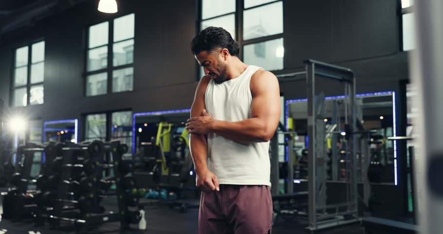 Man, fitness and arm with injury in gym for muscle tension, joint ache or inflammation. Male person, strain or cramp with pain, discomfort or fibromyalgia for pressure, intense workout or accident