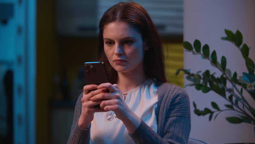 Angry mad Caucasian woman chatting mobile phone annoyed furious girl female housewife tenant homeowner using cellphone night home apartment problem bad service negative emotions texting message anger