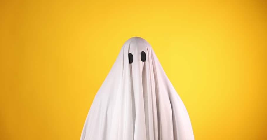 Creepy ghost. Man covered with white sheet showing scary moves on orange background