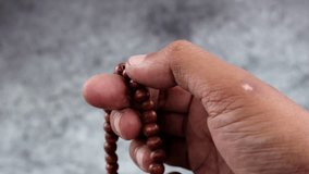 Close up of hands reciting dhikr using prayer beads with blurred background. Dzikir hand - Powered by Shutterstock - Get 15% off with code: PIKWIZARD15