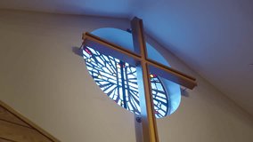 A tall wooden cross stands before a circular stained glass window in a quiet church sanctuary. - Powered by Shutterstock - Get 15% off with code: PIKWIZARD15