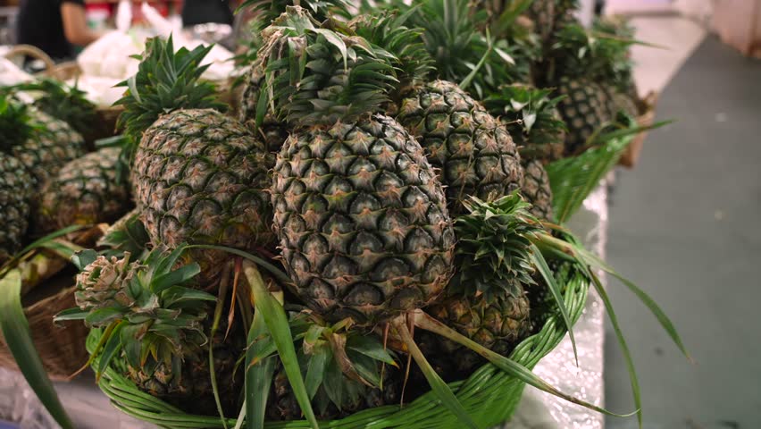 Pineapples with green crowns neatly arranged at local tropical fruit stand