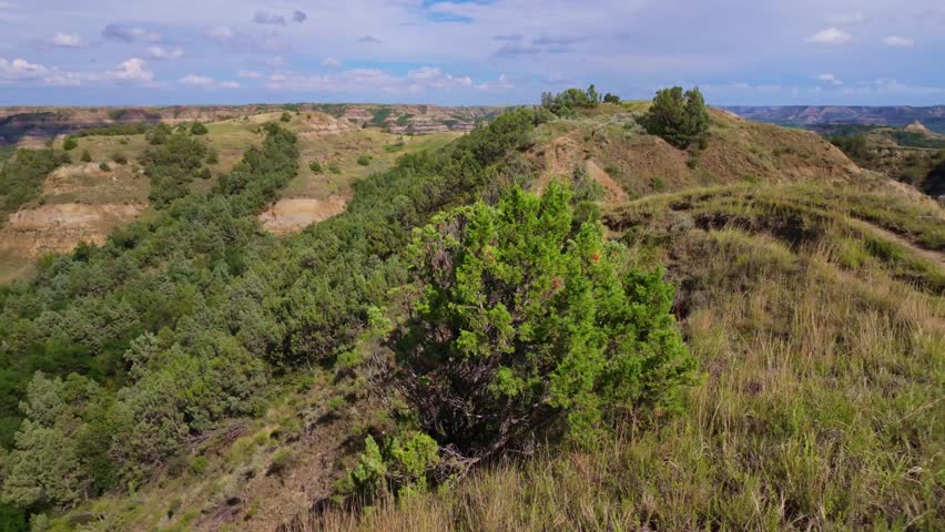 A sweeping panoramic view captures the dramatic landscapes along the Caprock Coulee Trail at Theodore Roosevelt National Park