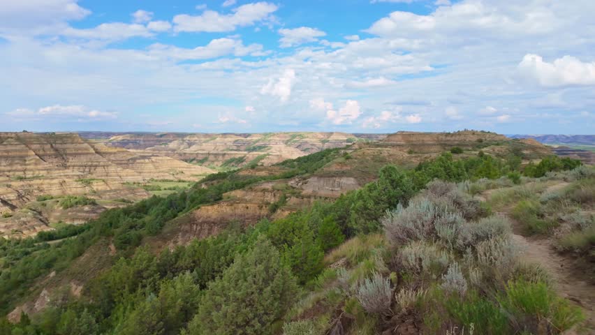 A sweeping panoramic view captures the dramatic landscapes along the Caprock Coulee Trail at Theodore Roosevelt National Park