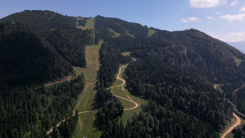 Summer aerial view of Poiana Brasov and Postavaru Mountain, Romania’s largest and most luxurious mountain resort, surrounded by lush forests and scenic Carpathian landscapes.