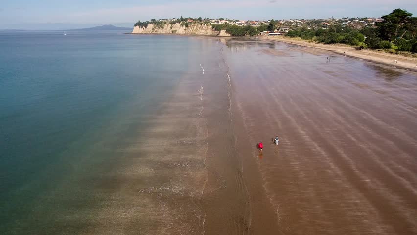 Aerial view of a low tide beachfront with cliffside homes in the background, showcasing the peaceful coastal scene of Son Tra Peninsula, Da Nang, Vietnam