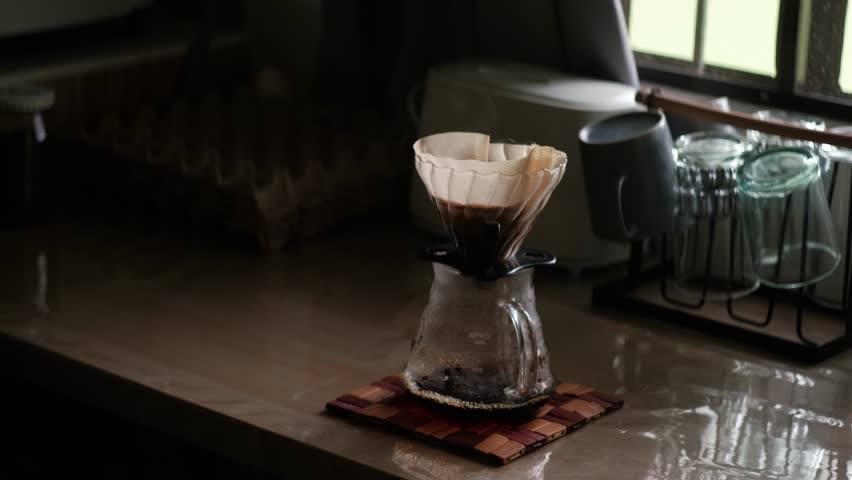 Brewed Coffee Dripping into Glass Carafe Through Pour-Over Filter Paper and V60 on Kitchen countertop - medium static shot
