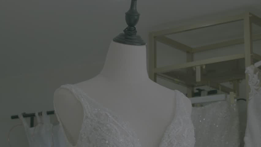 A chic bridal store showcases stunning wedding gowns on mannequins. Soft lighting enhances intricate lace and beadwork details in this elegant, serene setting. No people are present.