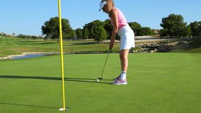 Skilled female golfer carefully sinking golf ball into hole on pristine putting green during sunny outdoor recreational activity - Powered by Shutterstock - Get 15% off with code: PIKWIZARD15
