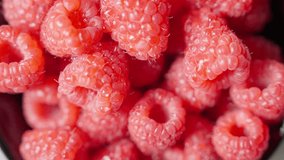 Close-up slow motion of fresh raspberries spinning in a bowl. One raspberry features a water droplet, top-down macro shot. - Powered by Shutterstock - Get 15% off with code: PIKWIZARD15