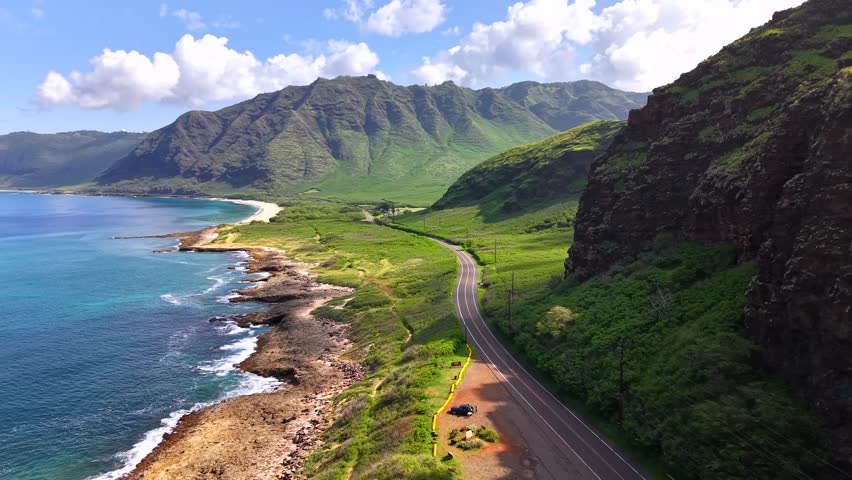 Scenic Farrington Highway winds between a cliff and the sea on Oahu, aerial