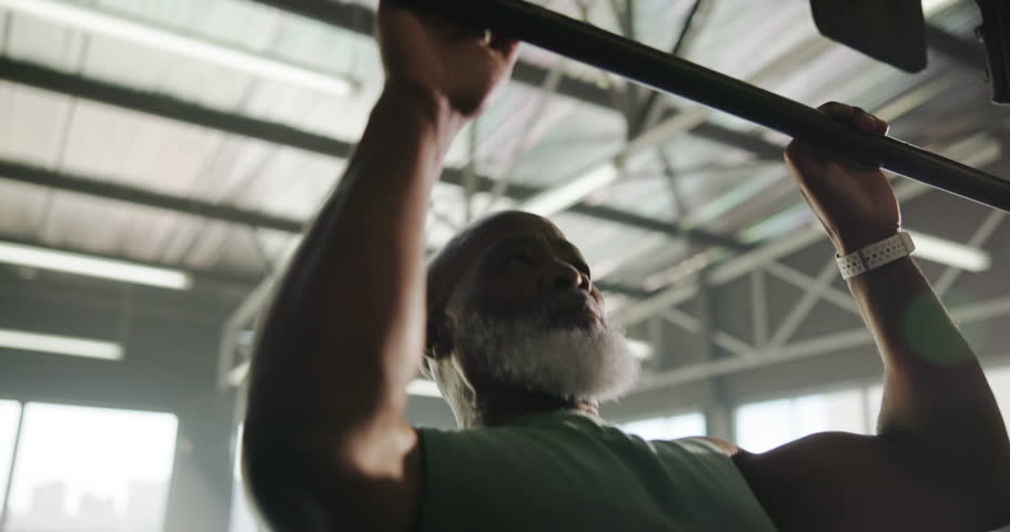 Gym, man and training with pull up bar, wellness or exercise for fitness, morning routine or active. Healthy, mature bodybuilder and black person with equipment for workout, body strength and muscle