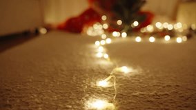 Woman in Santa Hat Sitting on Carpet in Pajamas Decorating Mini Tree with Lights in Cozy Living Room at Night. - Powered by Shutterstock - Get 15% off with code: PIKWIZARD15