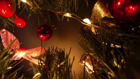 Hand Reaching Through Pine Tree to Touch Red Bauble Surrounded by Warm Lights and Ornaments Using Dolly Slider Angle Representing Holiday Decorating Tradition. - Powered by Shutterstock - Get 15% off with code: PIKWIZARD15