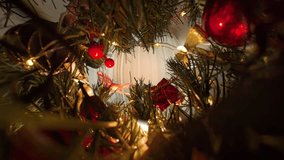 Hand Hanging Red Ornament on Tree Surrounded by Berries and Ribbons with Lights in a Close Up Dolly Slider Frame Representing Christmas Tree Decorating. - Powered by Shutterstock - Get 15% off with code: PIKWIZARD15