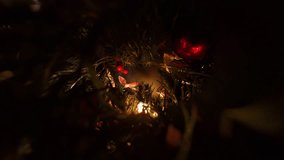 Hand Hanging Red Ornament Among Pine Branches with Glowing Lights and Ribbons in Zoomed View Representing Holiday Tree Decoration Tradition. - Powered by Shutterstock - Get 15% off with code: PIKWIZARD15