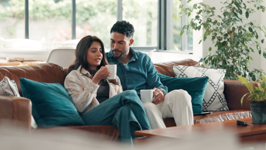 Couple, coffee and watching tv with talking on sofa for movie review, bonding and streaming service. Relax, people and drinking beverage in home with film subscription, weekend break or entertainment
