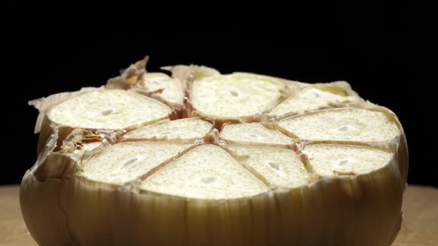 Macro Shot, Pouring Oil On Half Sliced Garlic Bulb Against Black Background, Slow Motion