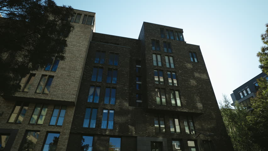 Minimalist building with high windows on brick shaded facade in HafenCity quarter low angle shot. Urban architect project of industrial houses redesigning in city