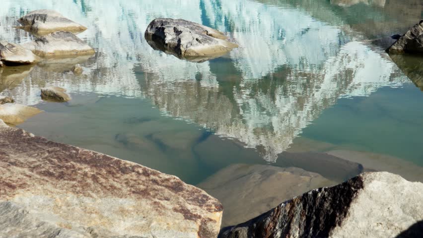 Glacial meltwater pool at the base of Mount San Lorenzo in Patagonia reflects snow covered mountain in turquoise water. Perito Moreno National Park, Santa Cruz, Patagonia.