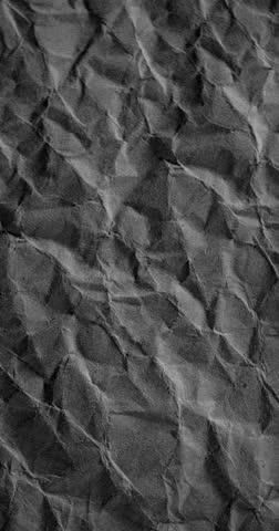 Dark Wrinkled Paper Texture Loop. Video featuring high-resolution rotating dark paper texture with folded triangular shapes and subtle seamless animation.