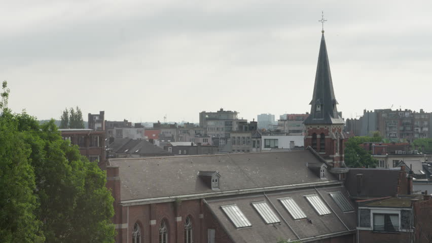A scenic daytime view over the rooftops of Antwerp, Belgium, with a prominent historic church in the foreground. Captured from an elevated perspective.