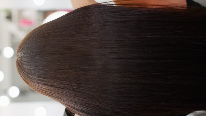 A vertical video showing well-groomed hair after a procedure in a beauty salon. Dyed hair shines with beauty. High quality 4k footage