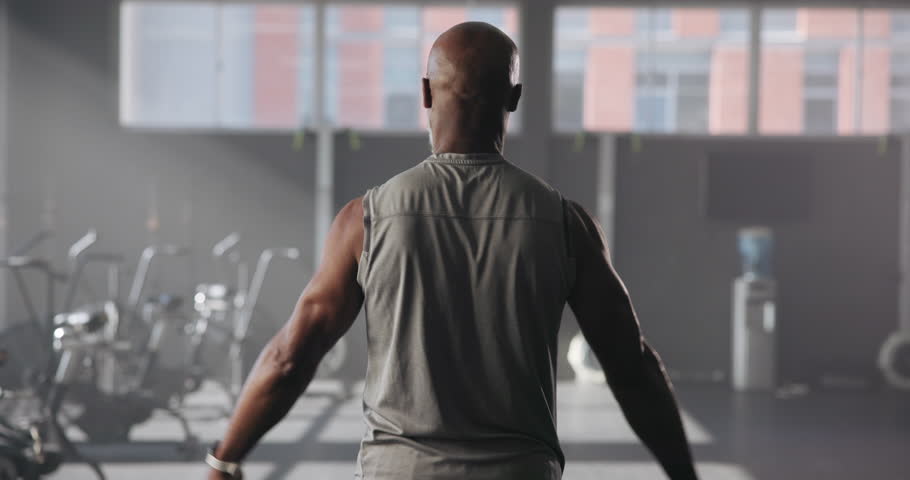 Exercise, black man and back view of flexing biceps, bodybuilder and fitness in gym. Athlete person, training and muscle goals for power, strength and pride for wellness and workout for progress