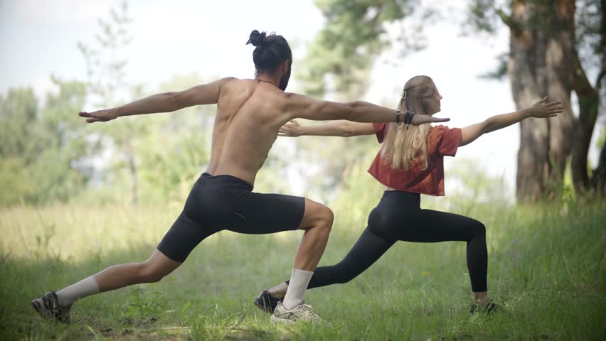 Couple Doing Yoga Warrior Pose. Man And Woman Exercising Together. Partner Fitness Workout. Yoga Pilates. Physical Wellness Outdoor Yoga Session. Body Strength Strong Core. Fitness Abdominal Exercise