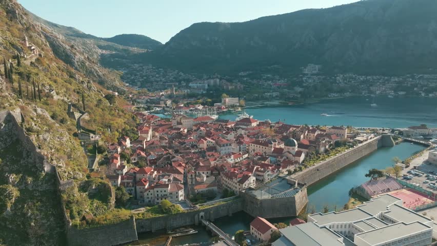 Aerial view of Kotor's historic old town and bay, showcasing medieval walls, red rooftops, and scenic coastline. A blend of heritage, architecture, and luxury Adriatic atmosphere.