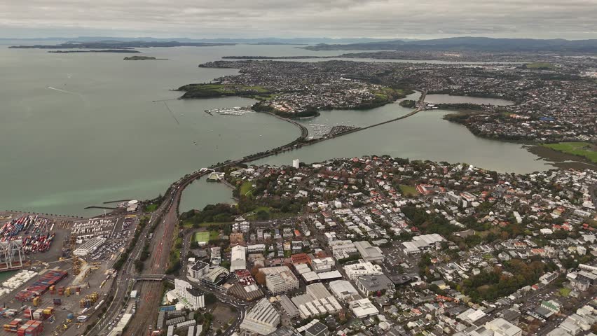 Auckland, New Zealand with Bridge and bays at sunset. Aerial panorama wide shot. Houses and homes in capital of nz. Suburbia and downtown in background.